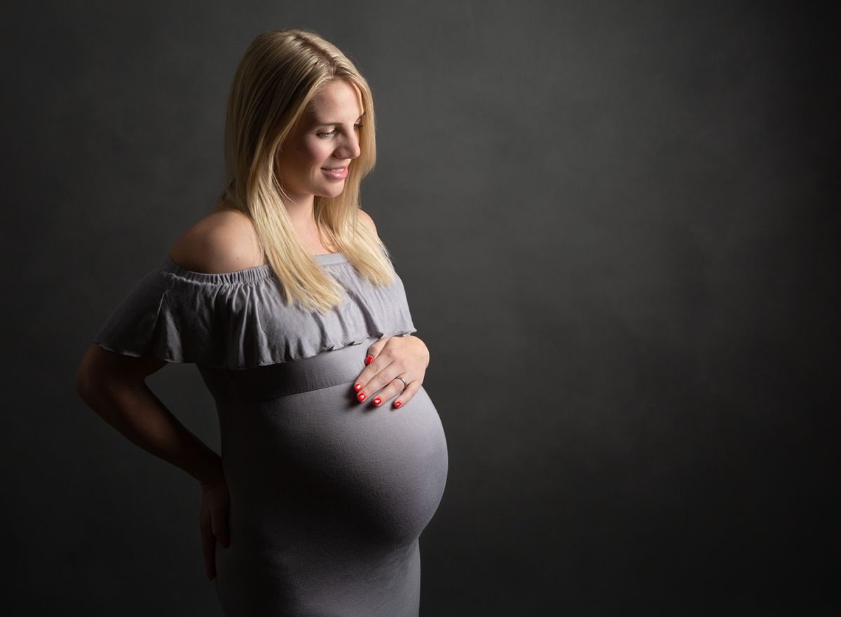 Pregnant women wearing a grey dress with hand on bump - Claire Walder Photography